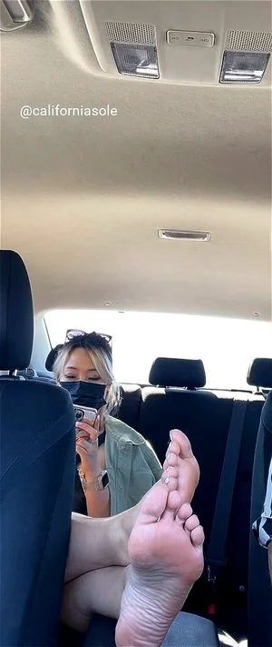 Asian passenger kicks her bare feet up in the car
