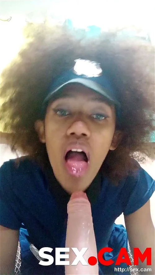 Curly police officer with blue eyes sucks a big dildo for her colleagues.